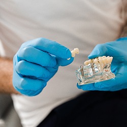 Dentist holding model of dental implants in Cary, NC