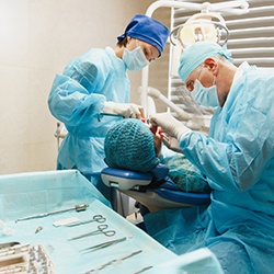 Patient leaning back in chair, oral surgeons performing a procedure