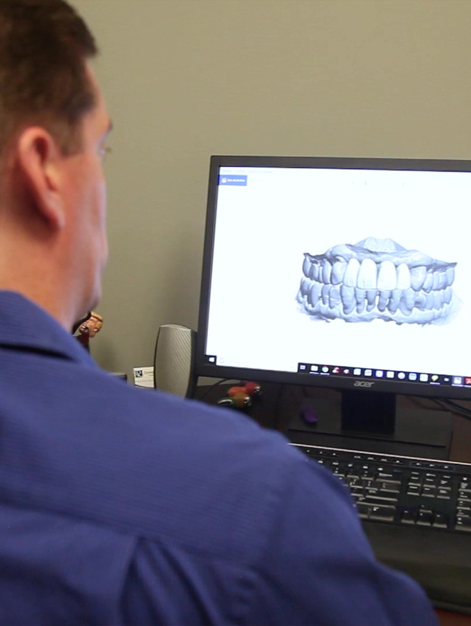 Dentist looking at digital model of teeth on computer screen