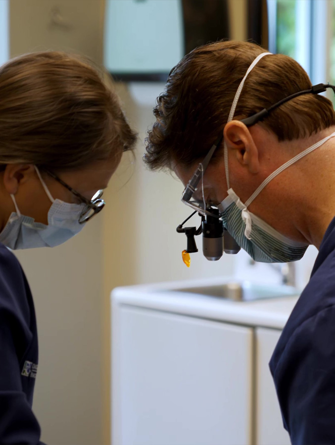 Dentist and dental team member wearing protective equipment while treating a patient