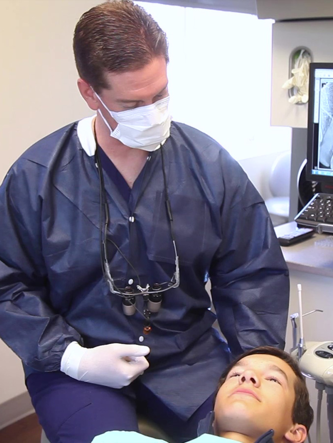 Dentist talking to young man in dental chair