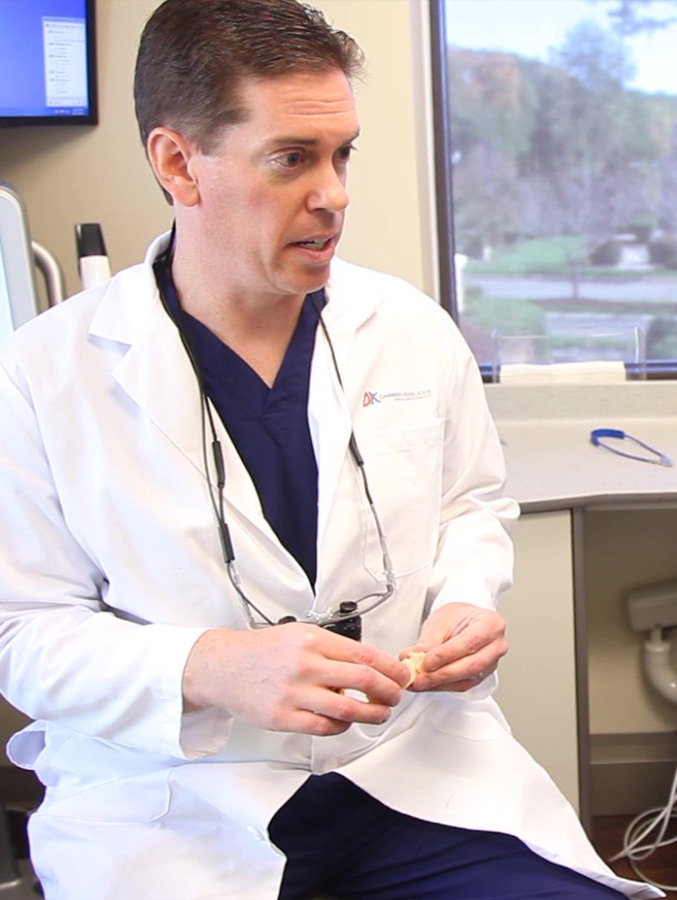 Dentist talking to patient while holding model of tooth