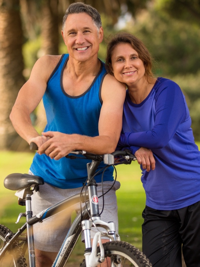 Older man and woman biking outdoors