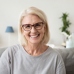 Senior woman with glasses smiling on couch