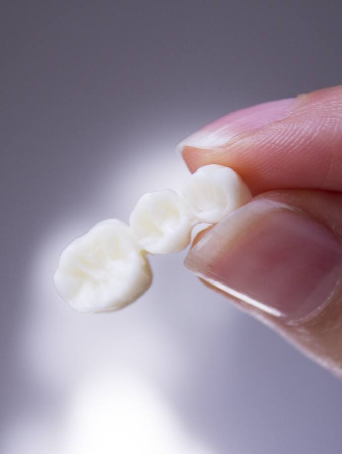 Close up of person holding a dental bridge