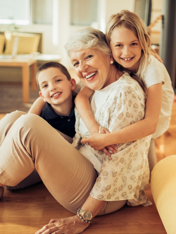 Senior woman with dentures in Cary laughing with her two grandkids