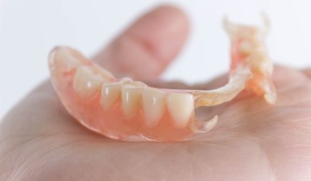 Person holding a partial denture in their hand