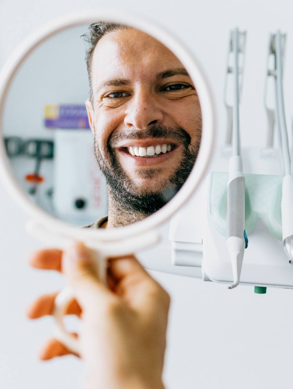 Man taking a look at his smile in a handheld mirror