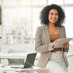 Smiling woman standing at home and holding a tablet