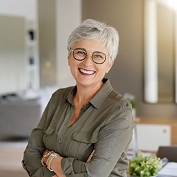 Senior woman with glasses smiling with her arms folded