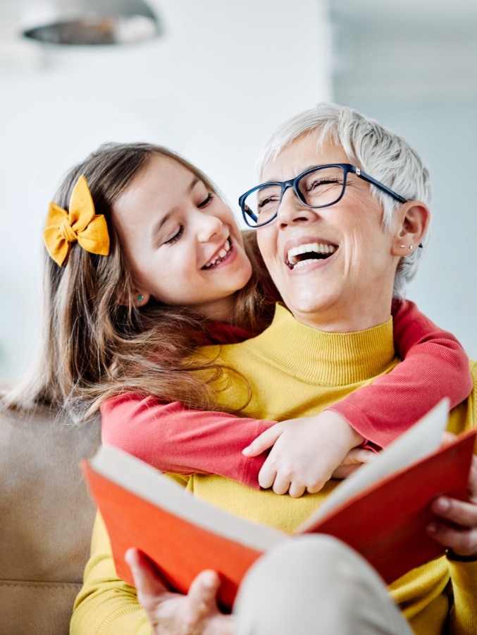 Senior woman reading on couch with granddaughter