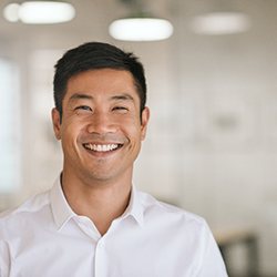 Man in white shirt standing in office and smiling