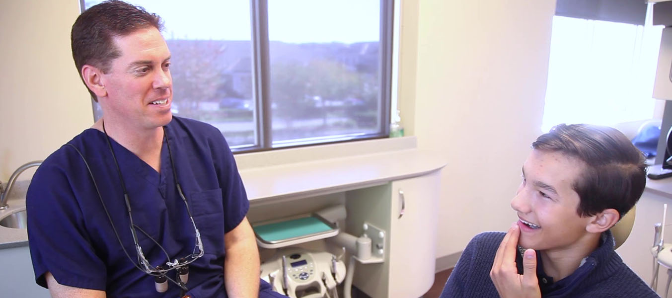 Cary dentist talking with young man in dental chair