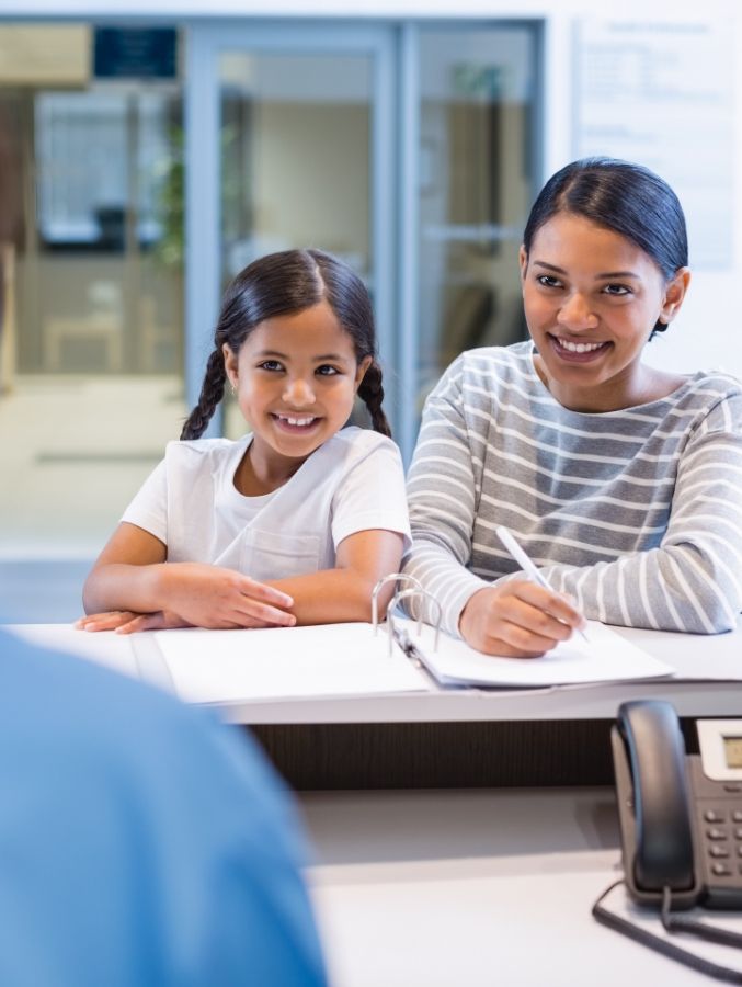 Woman with her child talking to dental team member about dental insurance in Cary