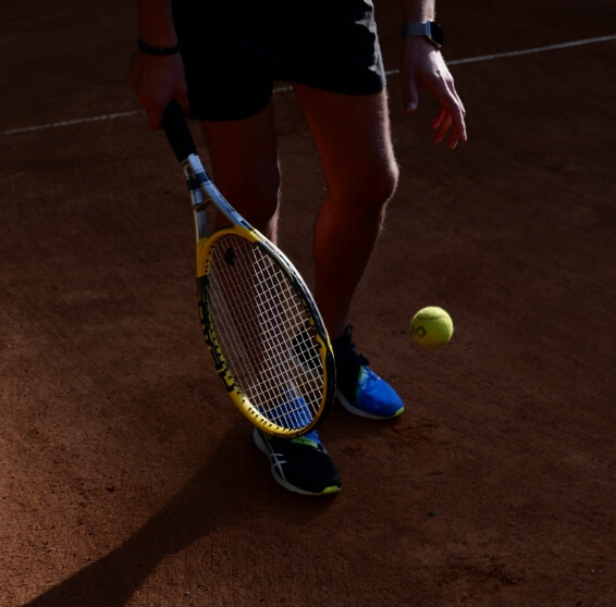 Person holding tennis racket in tennis court