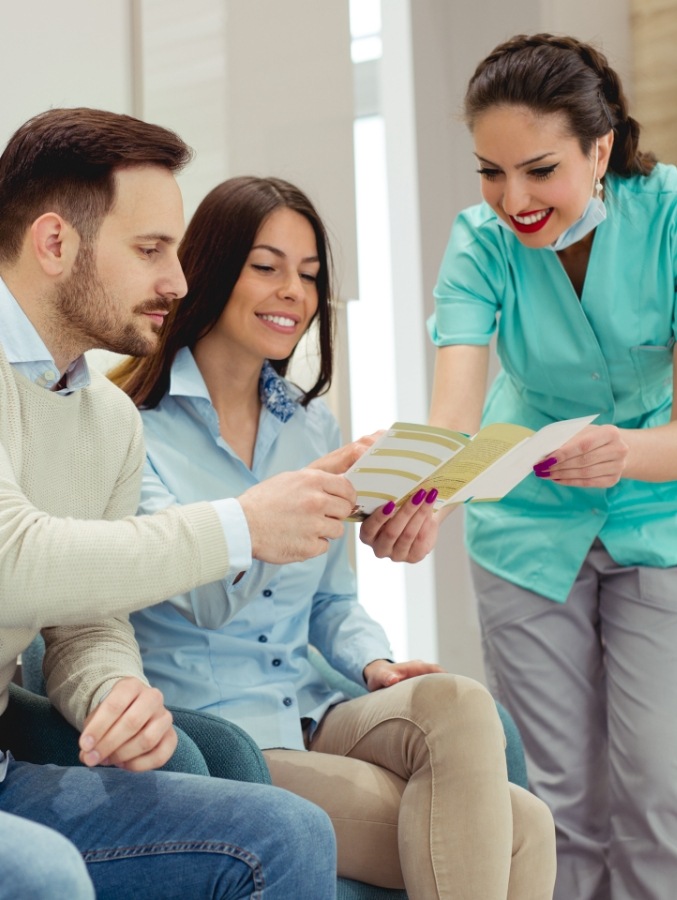 Dental team member telling two patients about dental membership plan in Cary