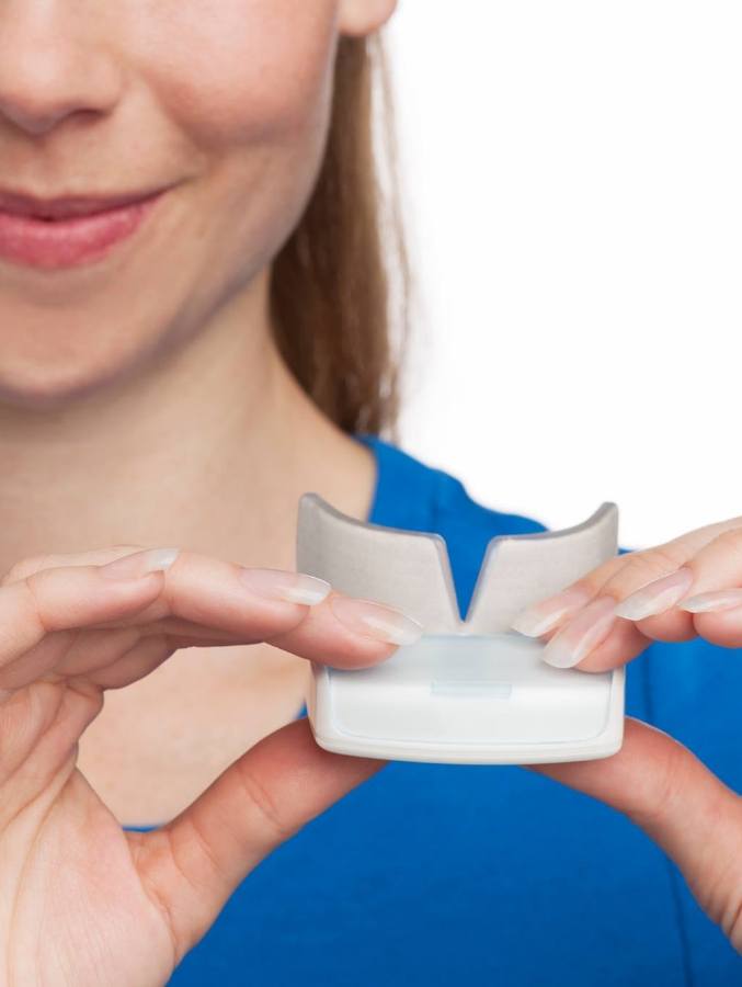 Woman holding OrthoPulse device in small box case