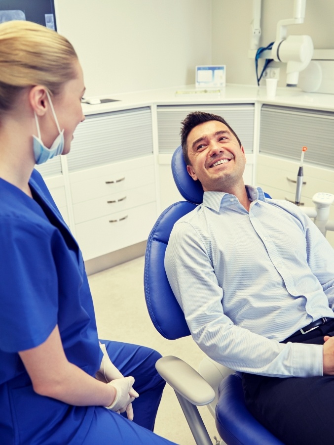 Man in dental chair smiling at dental team member