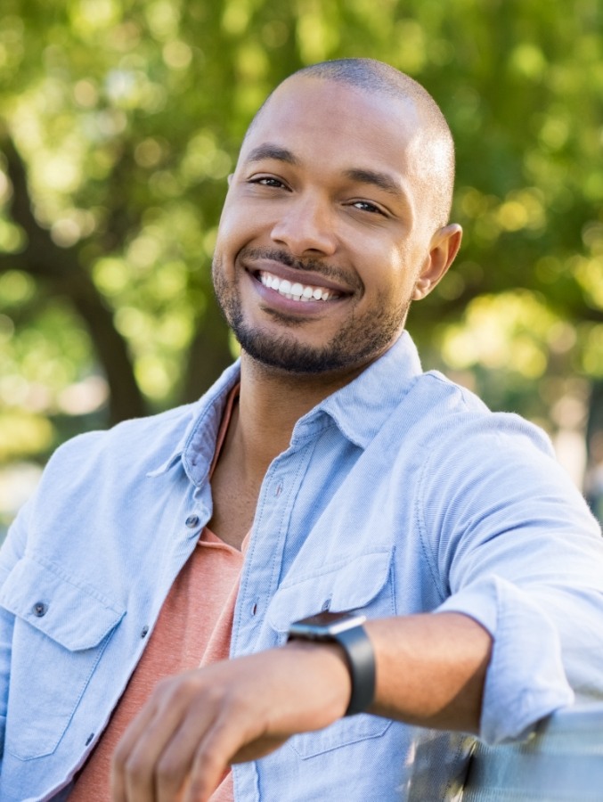 Man in light blue shirt smiling outdoors