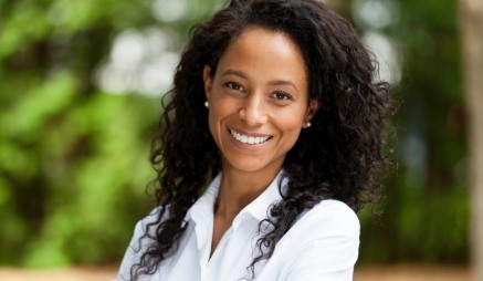 Woman in white collared shirt smiling outdoors