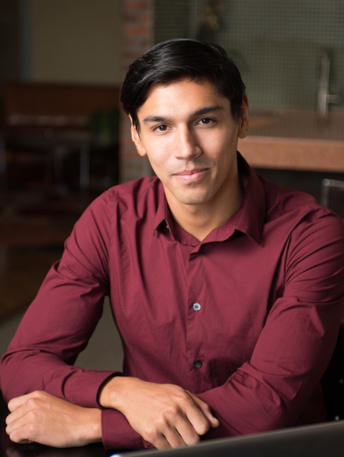 Young man in red button up shirt sitting at table