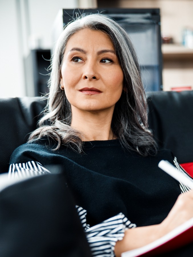 Woman with veneers in Cary sitting on couch with book