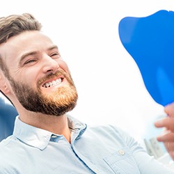 Male patient checking his smile in a handheld mirror