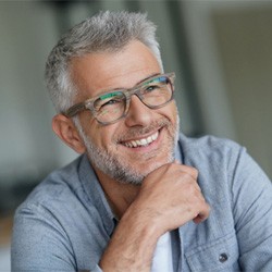 Senior man with glasses smiling with hand on chin