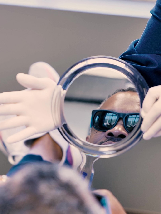 Reflection of dental patient wearing sunglasses in hand mirror