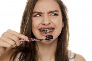 a woman using charcoal to brush her teeth