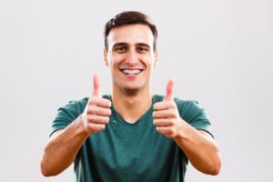 man with clean thumbs up thanks to his dentist