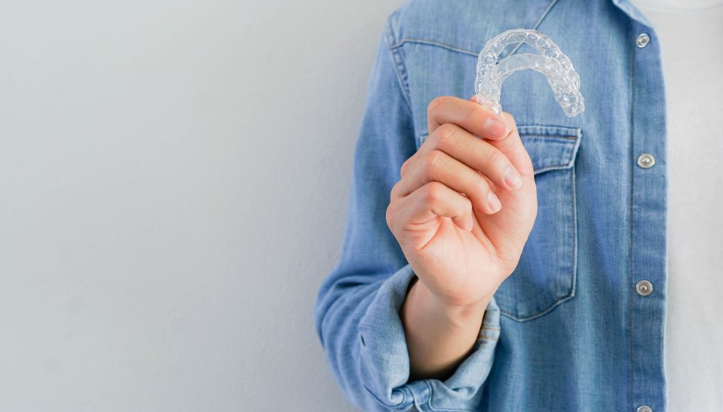 Patient holding up their Invisalign clear aligners