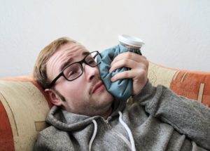 man using an ice pack for his toothache at night 