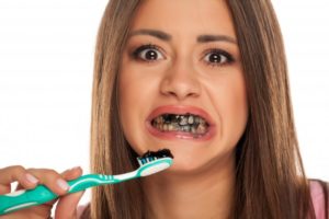 Woman brushing her teeth with charcoal