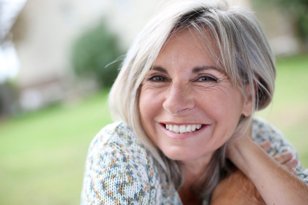 Older woman with dental implants smiling.