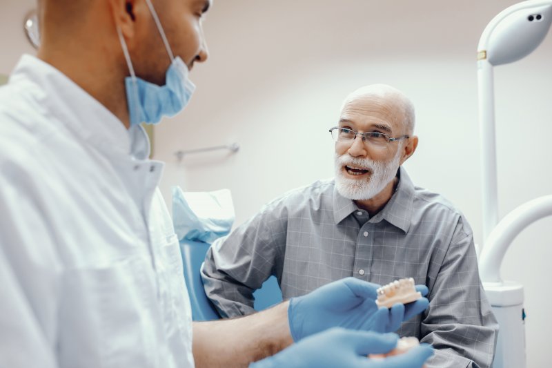 Senior man sitting in the dentist's office, talking about dental implants.