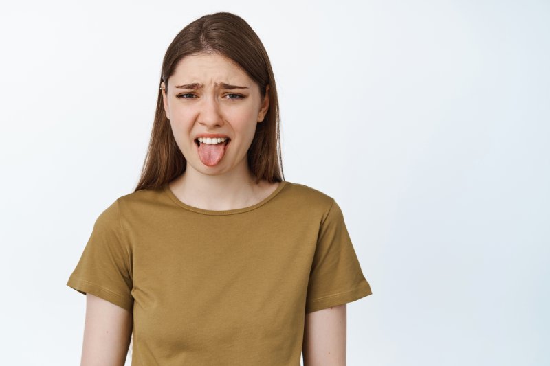 a woman showing tongue due to bitter taste in mouth