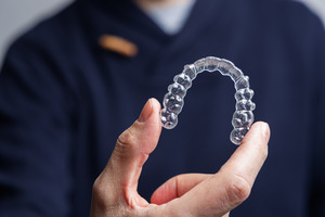 Close-up of a man holding an Invisalign aligner