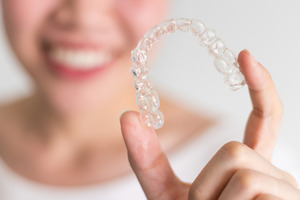 Woman holding a single Invisalign aligner